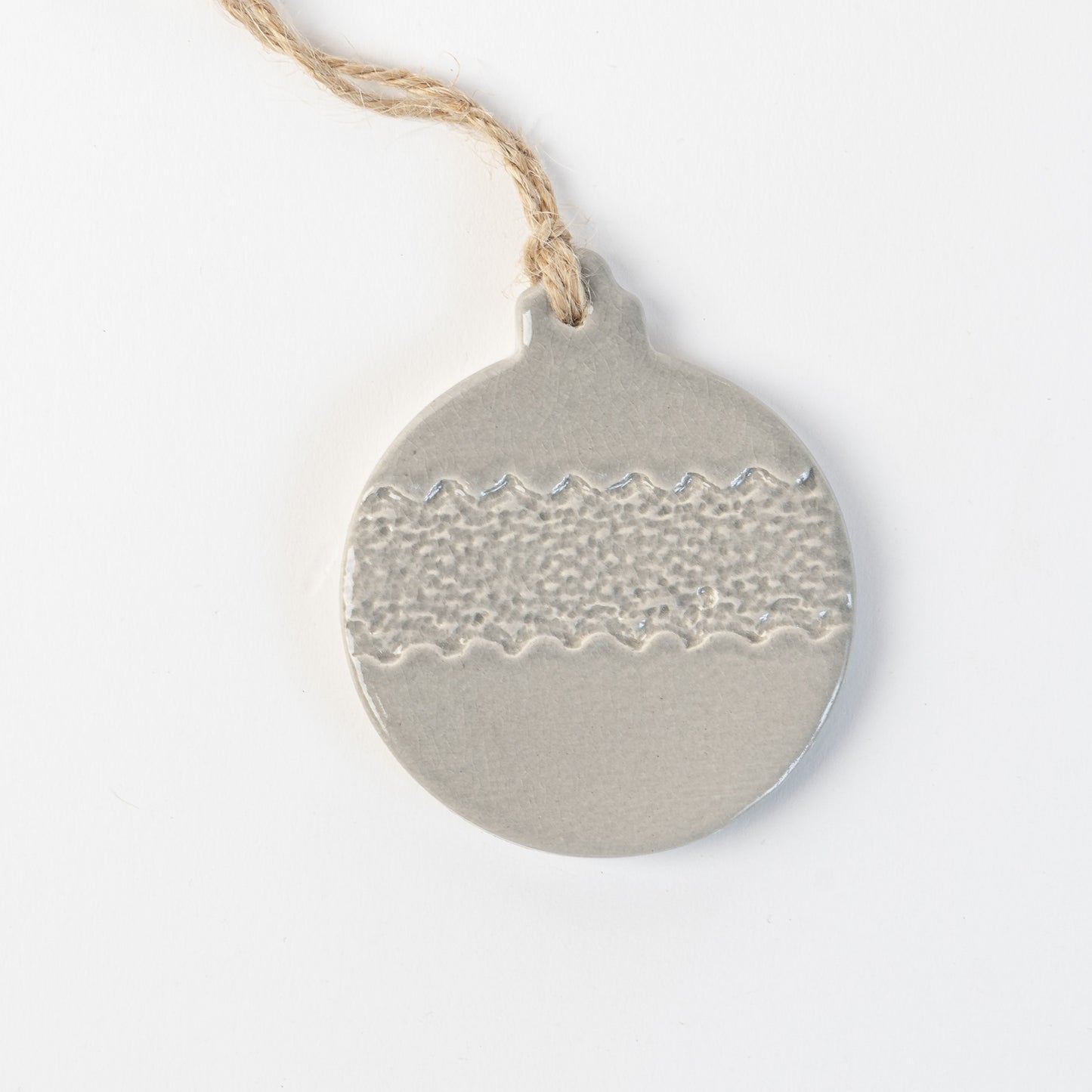 Grey frost textured ceramic bauble ornament hanging on a white background made by the wirksworth pottery company