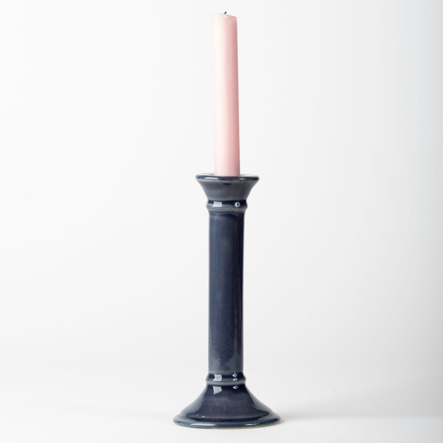 Black candle holder with a pink candle on a white background