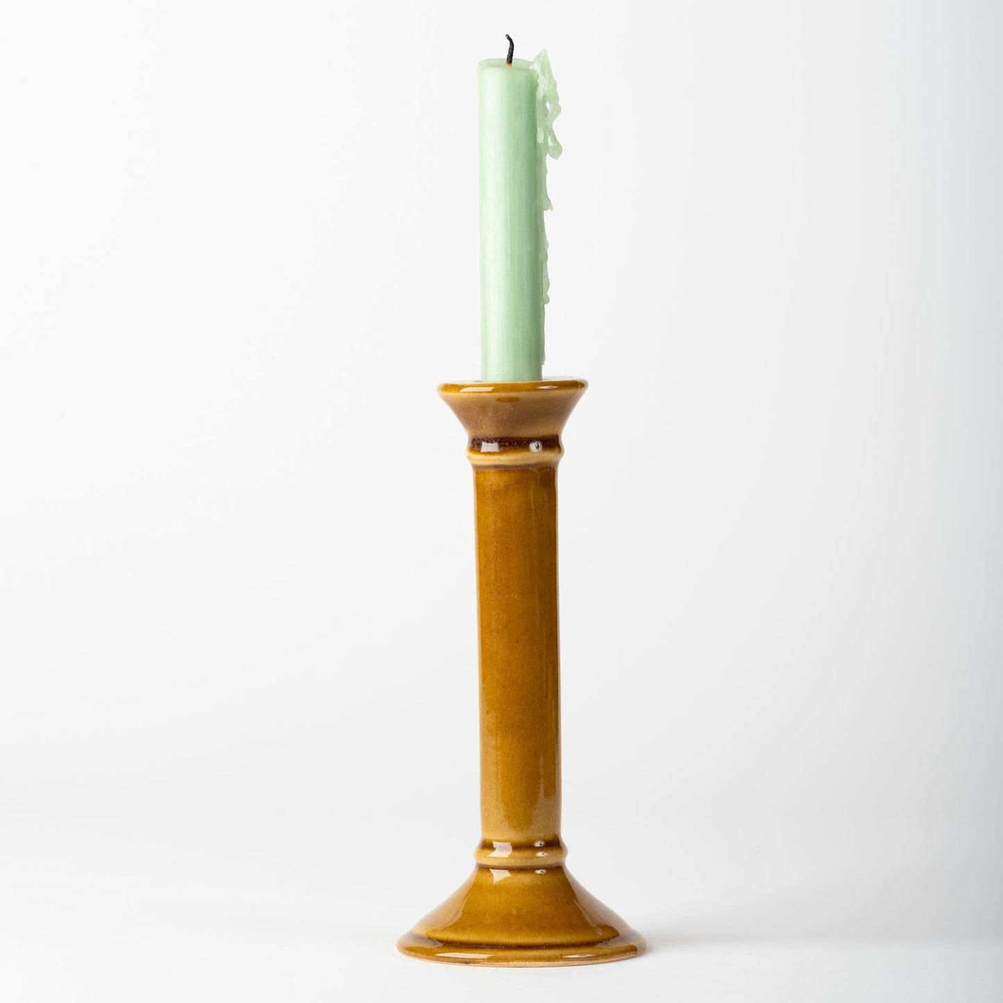 Green candle in a gold candle holder on a white background