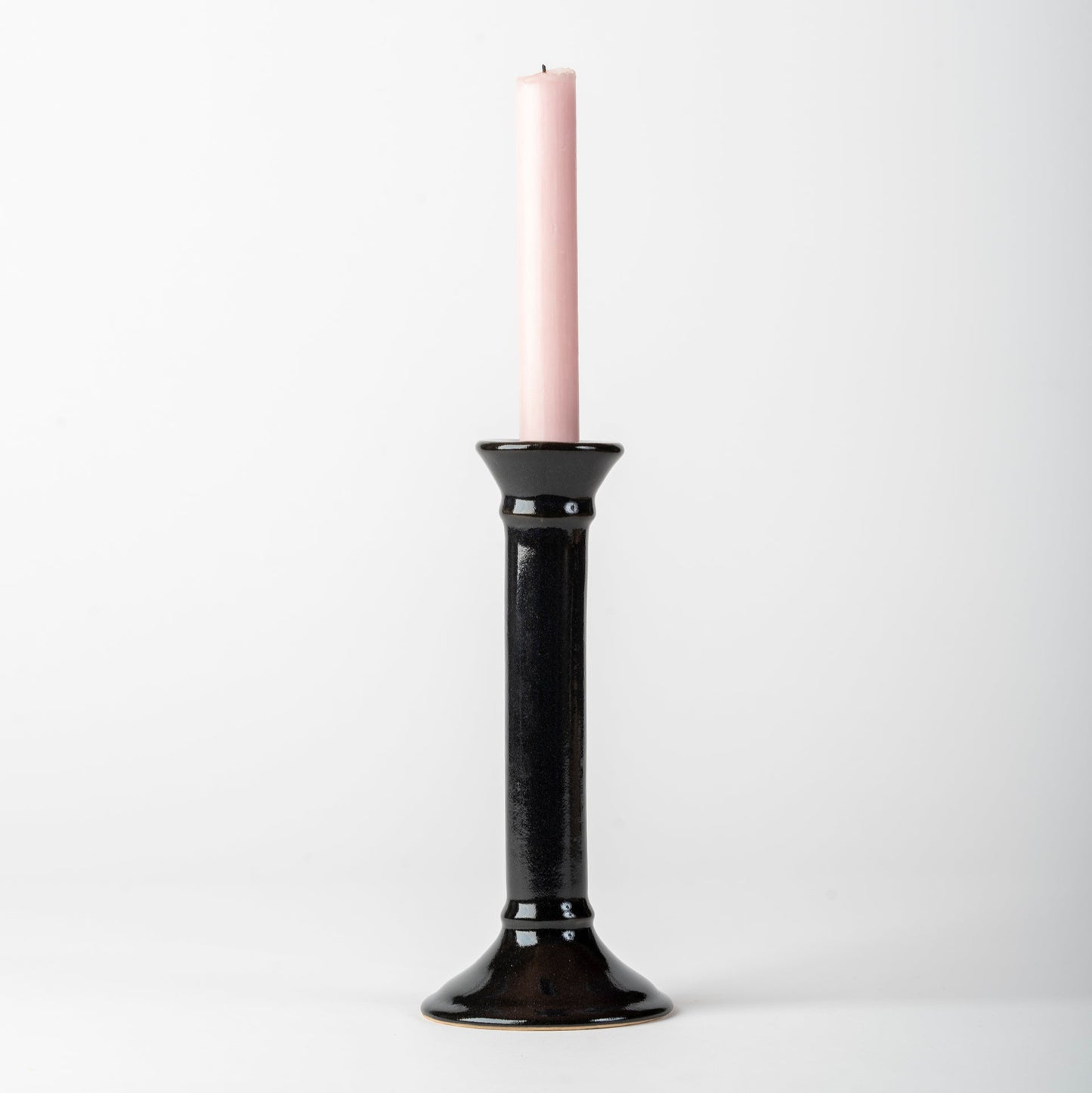 Black candle holder with a pink candle on a white background