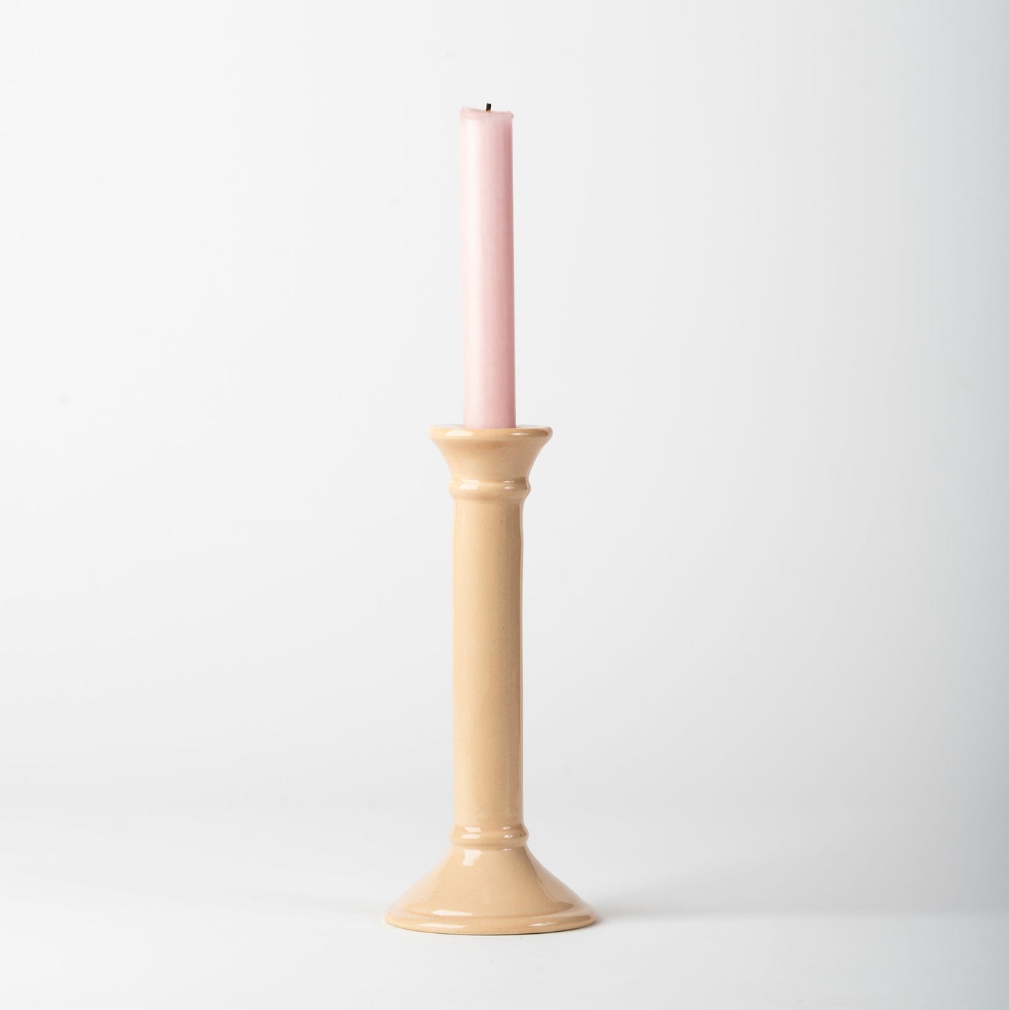 Beige candle holder with a pink candle on a white background