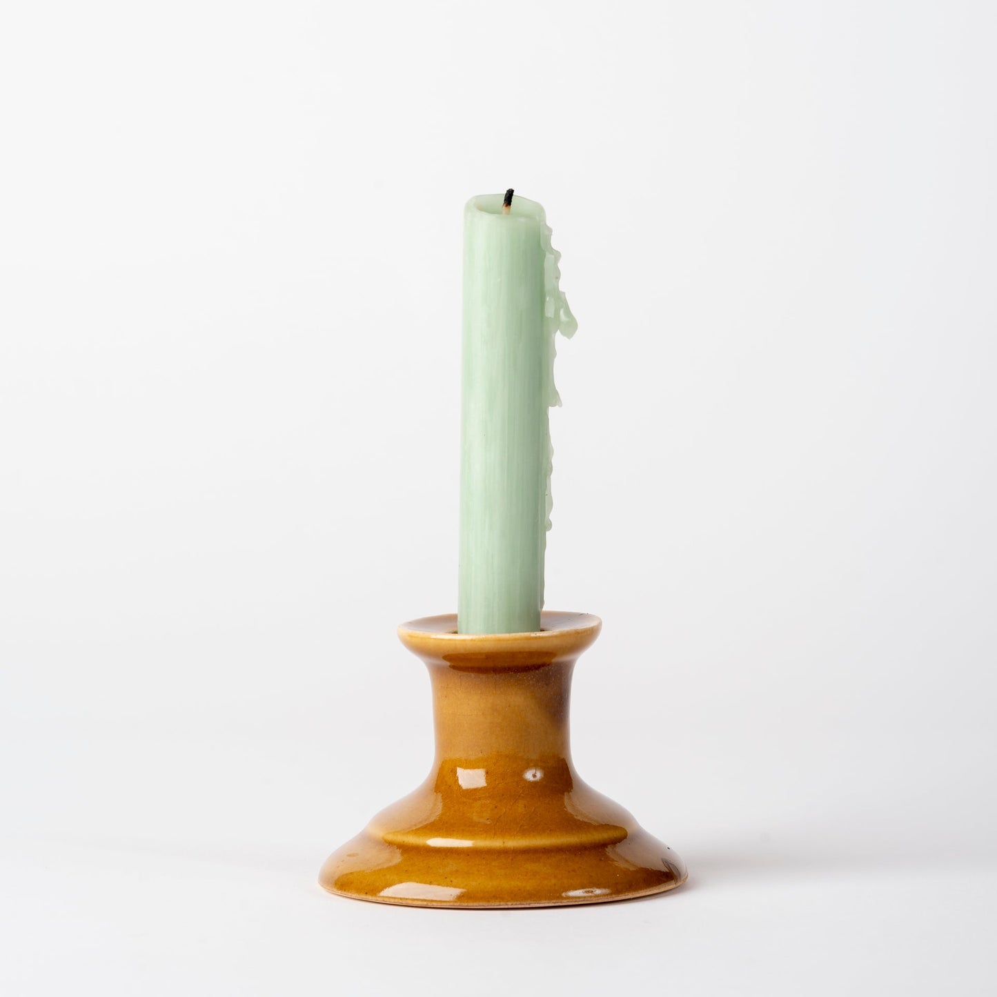 Candle in a brown ceramic holder on a white background