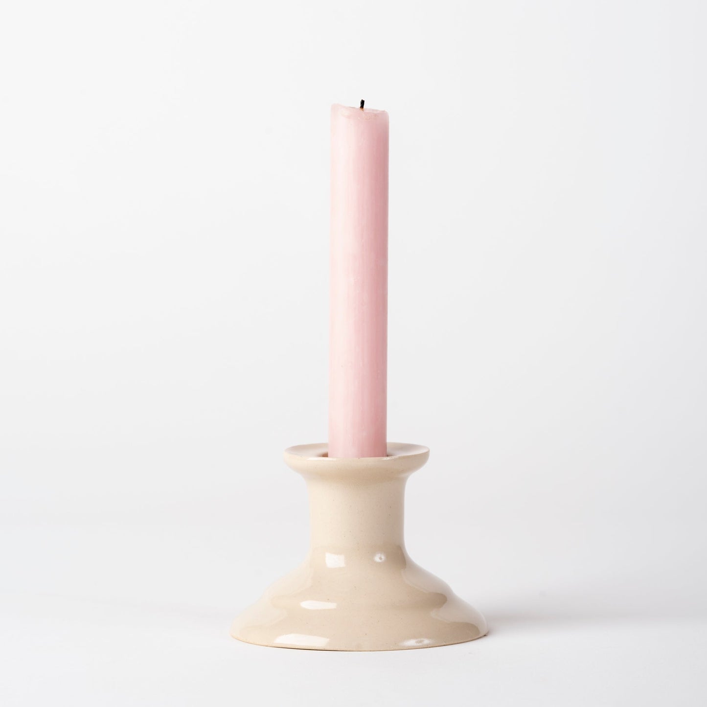 Pink candle in a beige candle holder on a white background