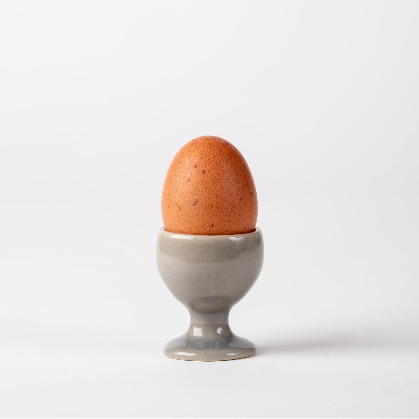 Brown egg in a gray egg cup on a white background