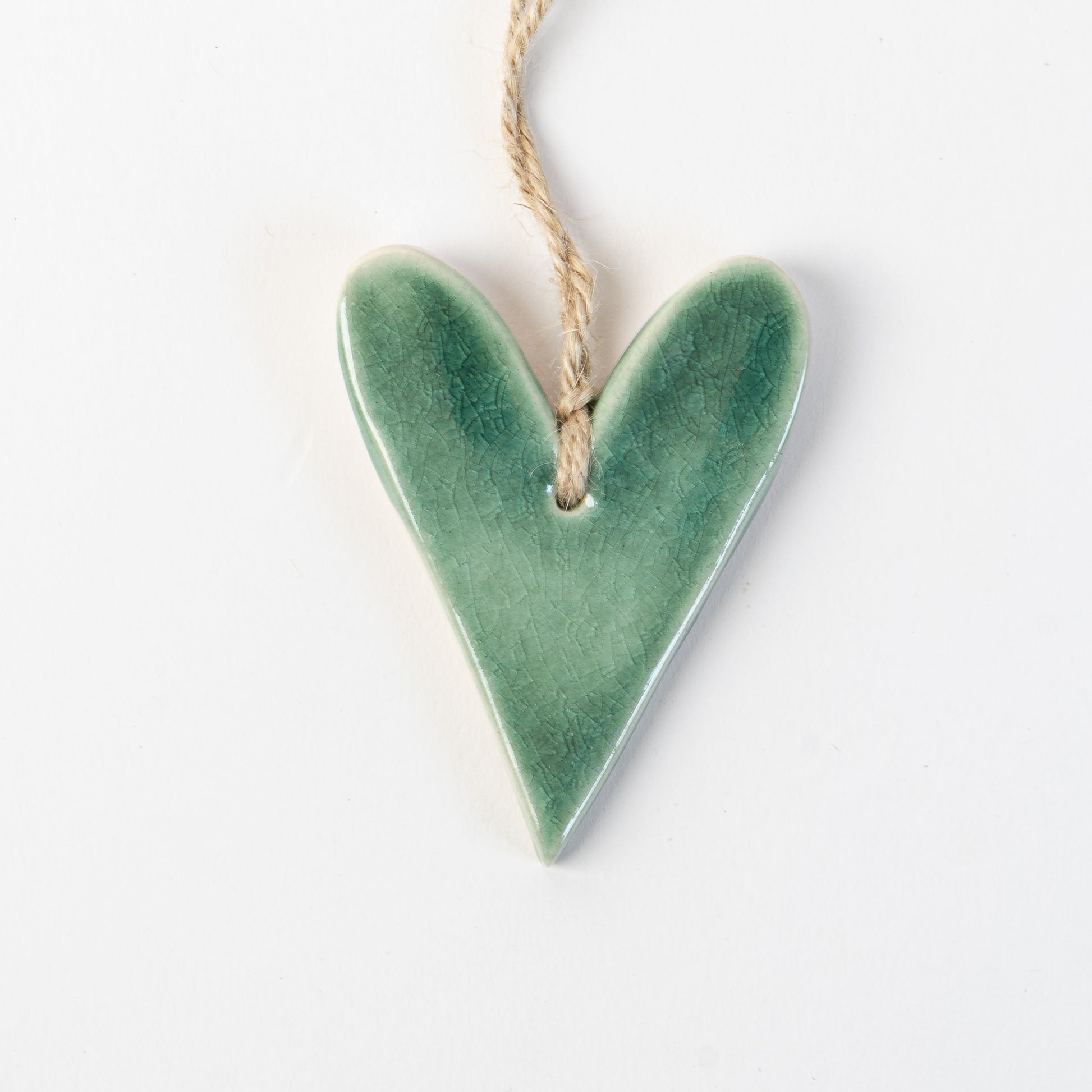 Fir Green Heart-shaped ceramic ornament hanging on a rope against a white background