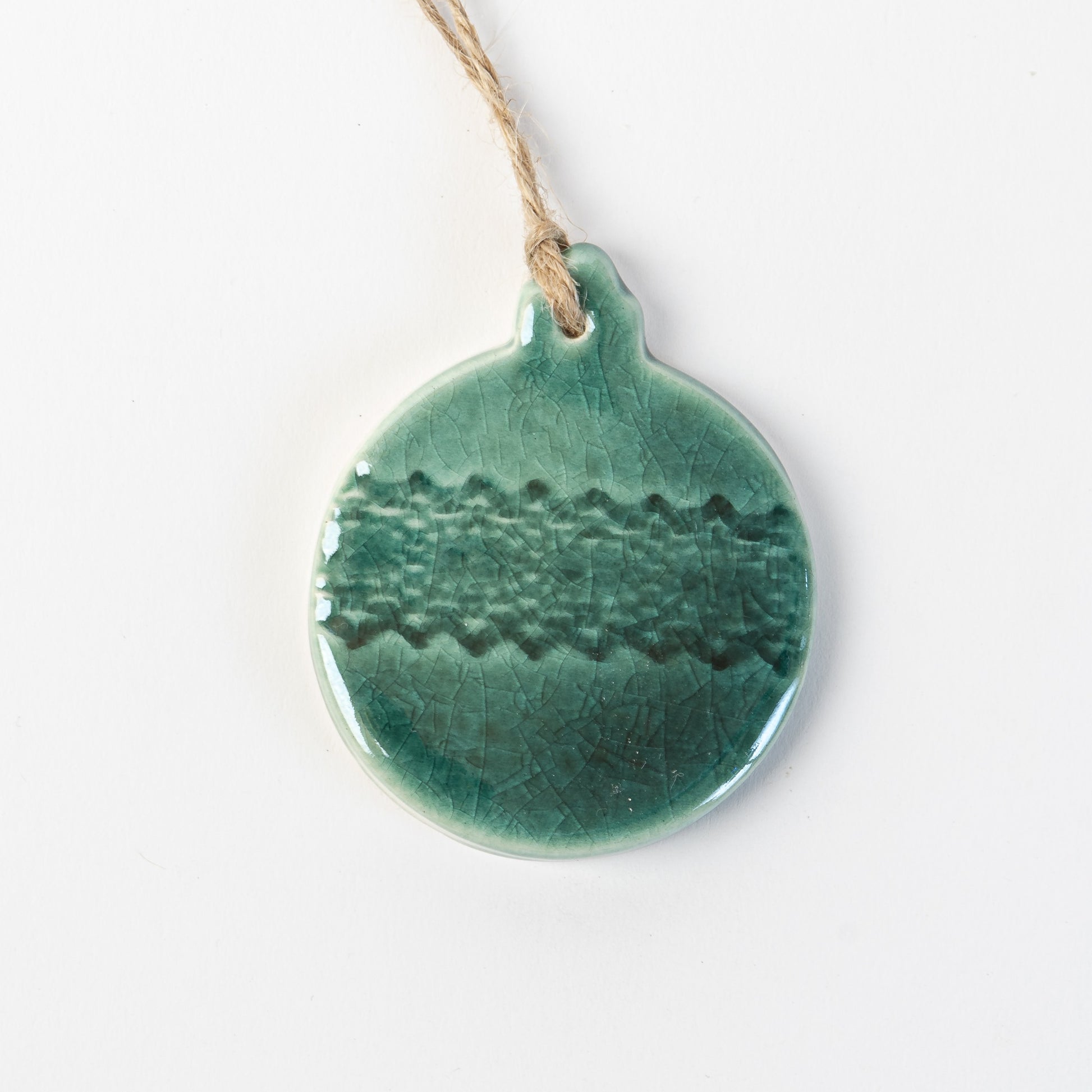 fir green textured ceramic bauble ornament hanging on a white background made by the wirksworth pottery company