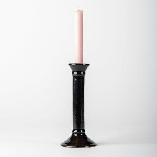 Black candle holder with a pink candle on a white background