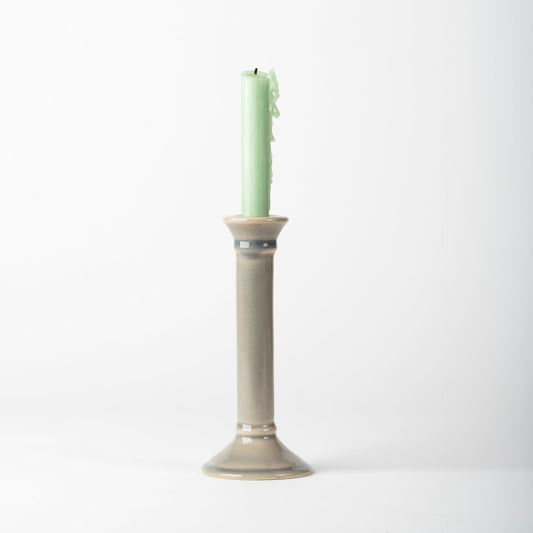 Green candle in a beige holder on a white background