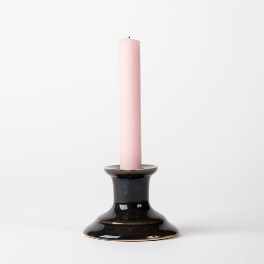 Black candle holder with a pink candle on a white background