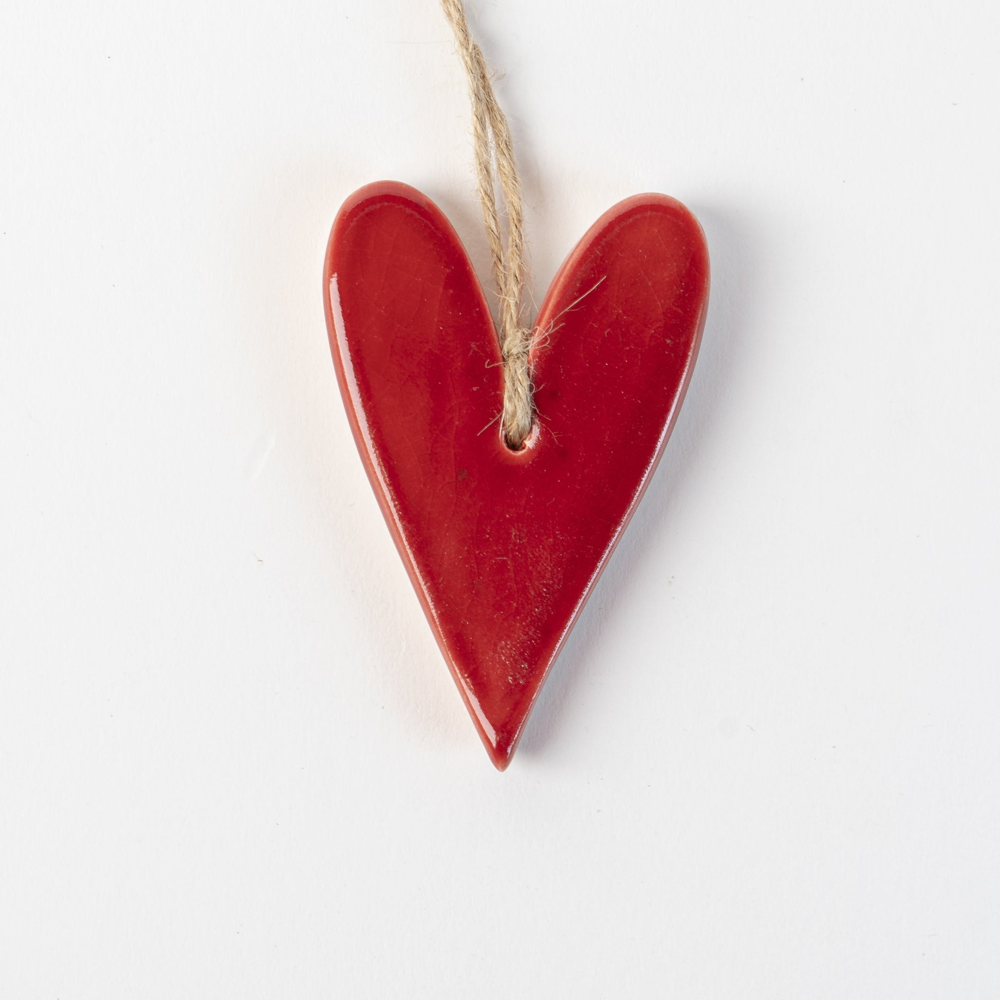 Red Heart-shaped ceramic ornament with string on white background