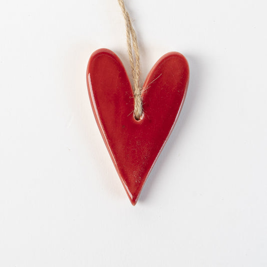 Red Heart-shaped ceramic ornament with string on white background