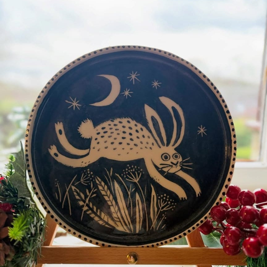 Decorative plate with a rabbit design on a stand in front of a window