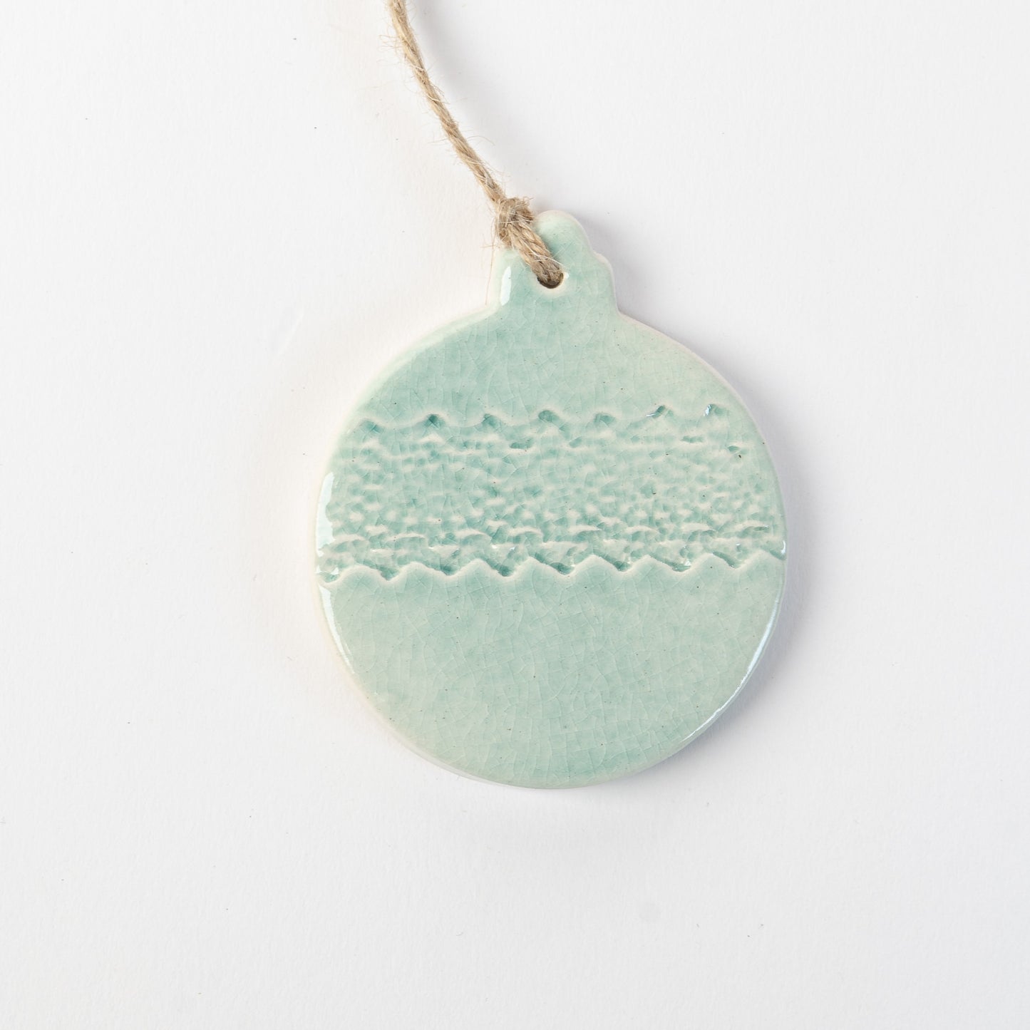 Pale blue textured ceramic bauble ornament hanging on a white background made by the wirksworth pottery company