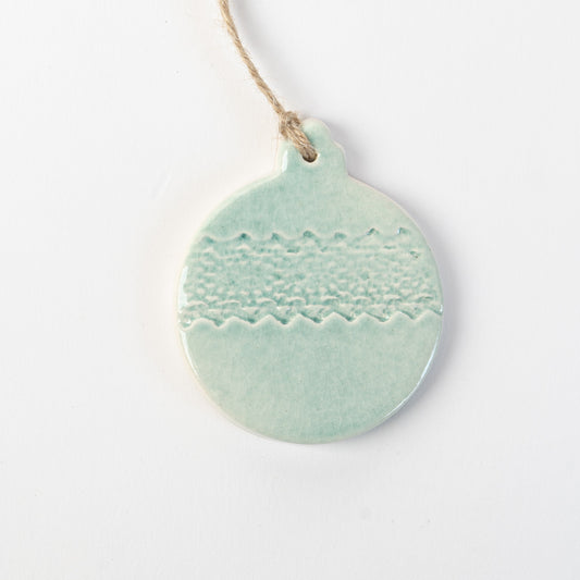 Pale blue textured ceramic bauble ornament hanging on a white background made by the wirksworth pottery company