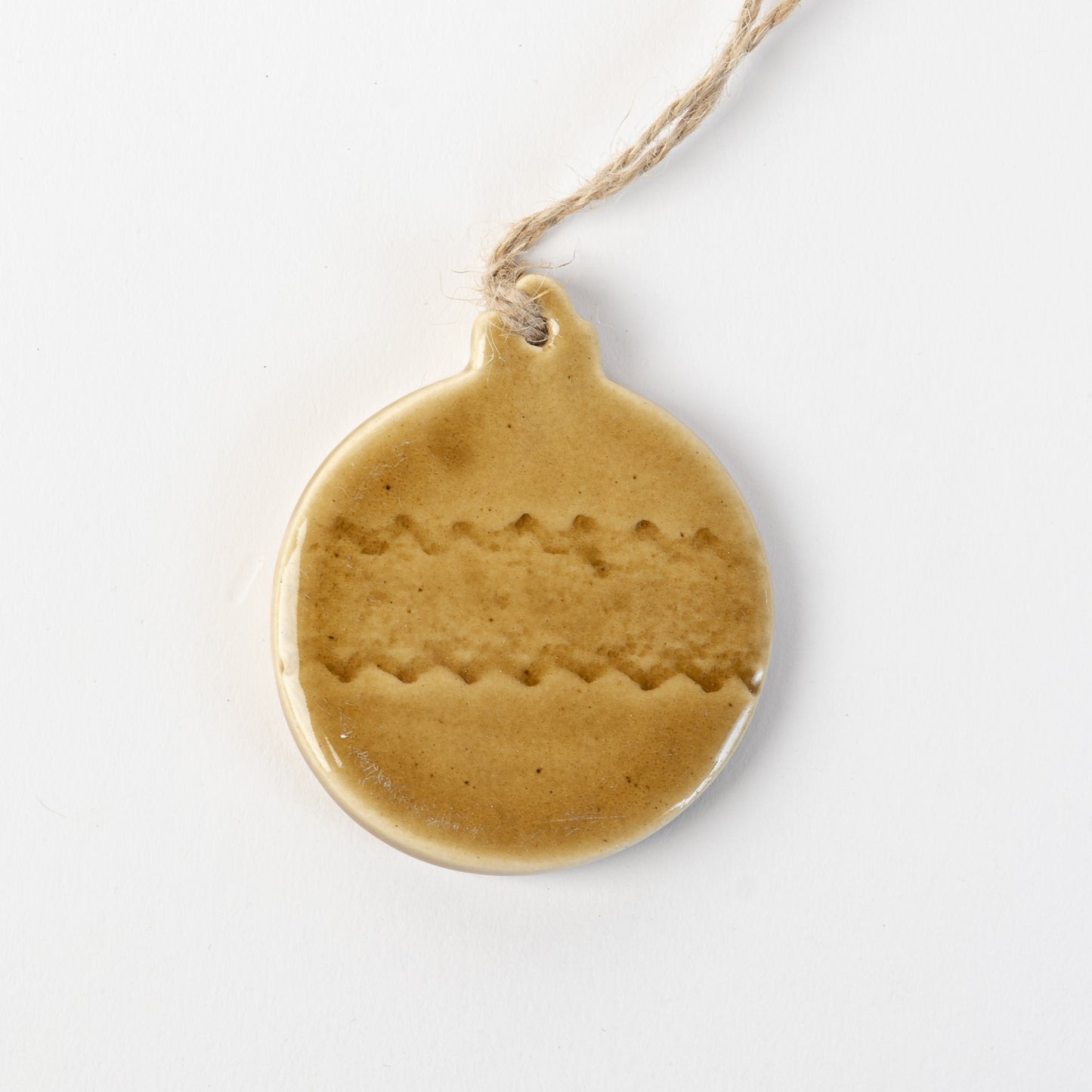 Golden yellow textured ceramic bauble ornament hanging on a white background made by the wirksworth pottery company