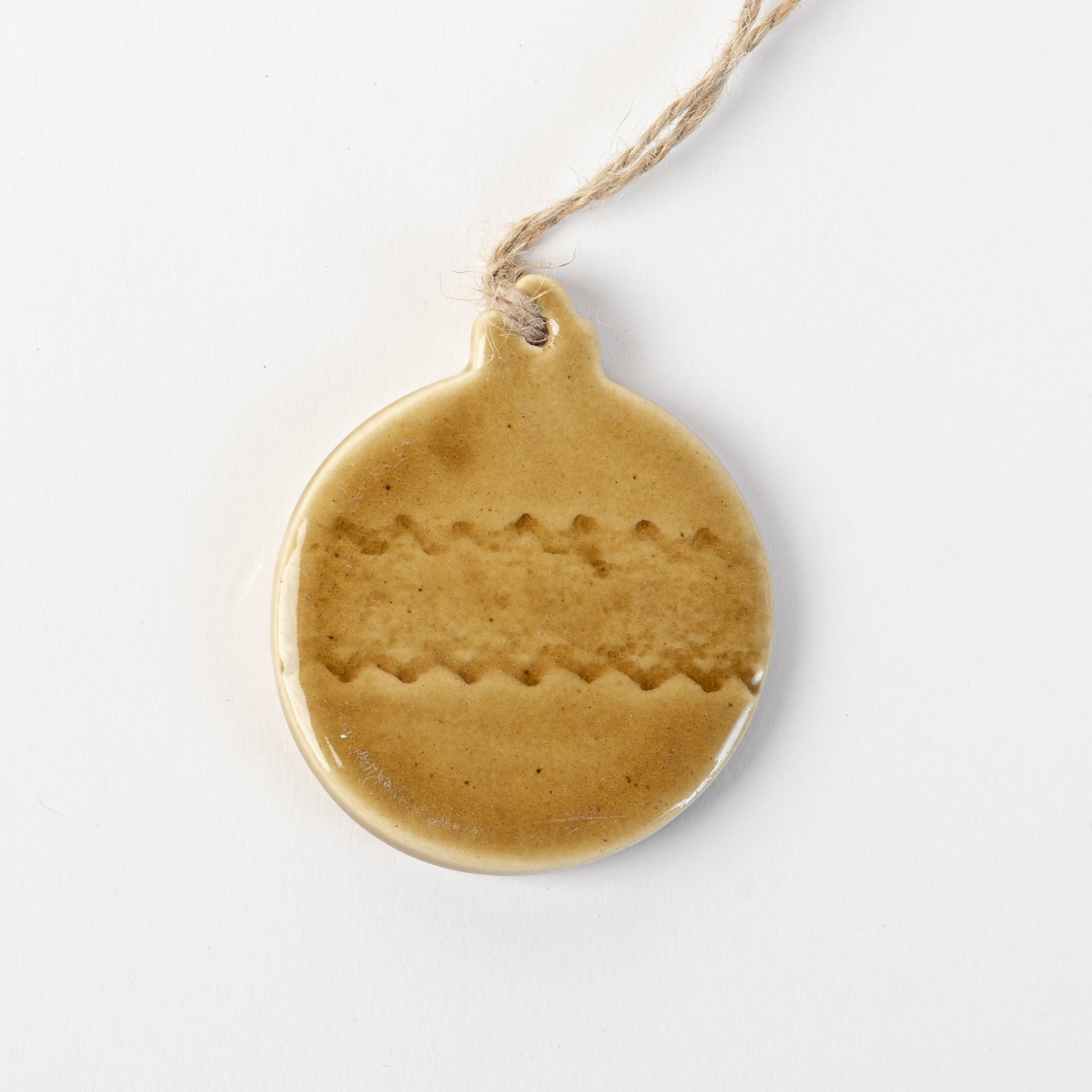 Golden yellow textured ceramic bauble ornament hanging on a white background made by the wirksworth pottery company