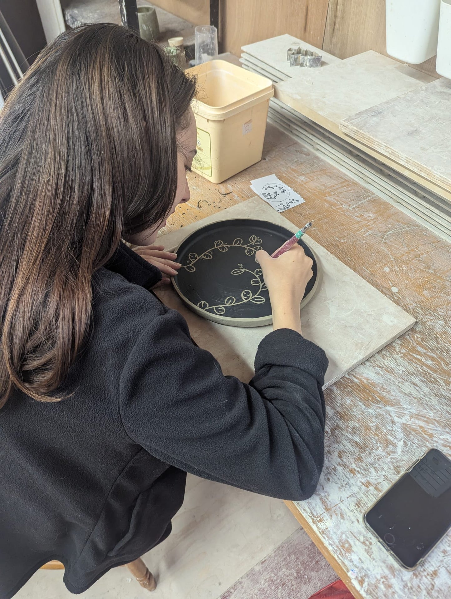 Person working on a sgraffito plate in a workshop - the wirksworth pottery company